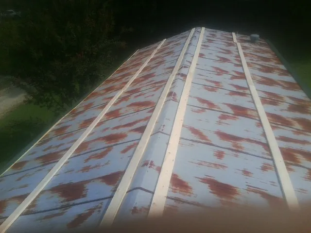 Rusted metal roof panels with new wood purlins before replacement — Storm Damage Roof Repair in Country Club Hills by Roofing Brothers