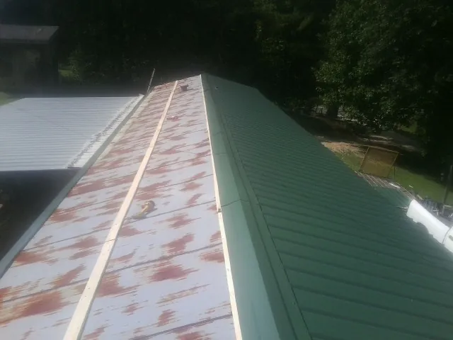 Old rusted panels beside newly installed green metal roofing — Wind Damage Roof Repair by Roofing Brothers in Country Club Hills