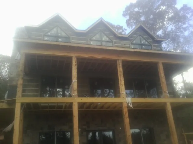 Dormers and porch framing on a large log home under construction — Roof Coating work by our crew in Country Club Hills