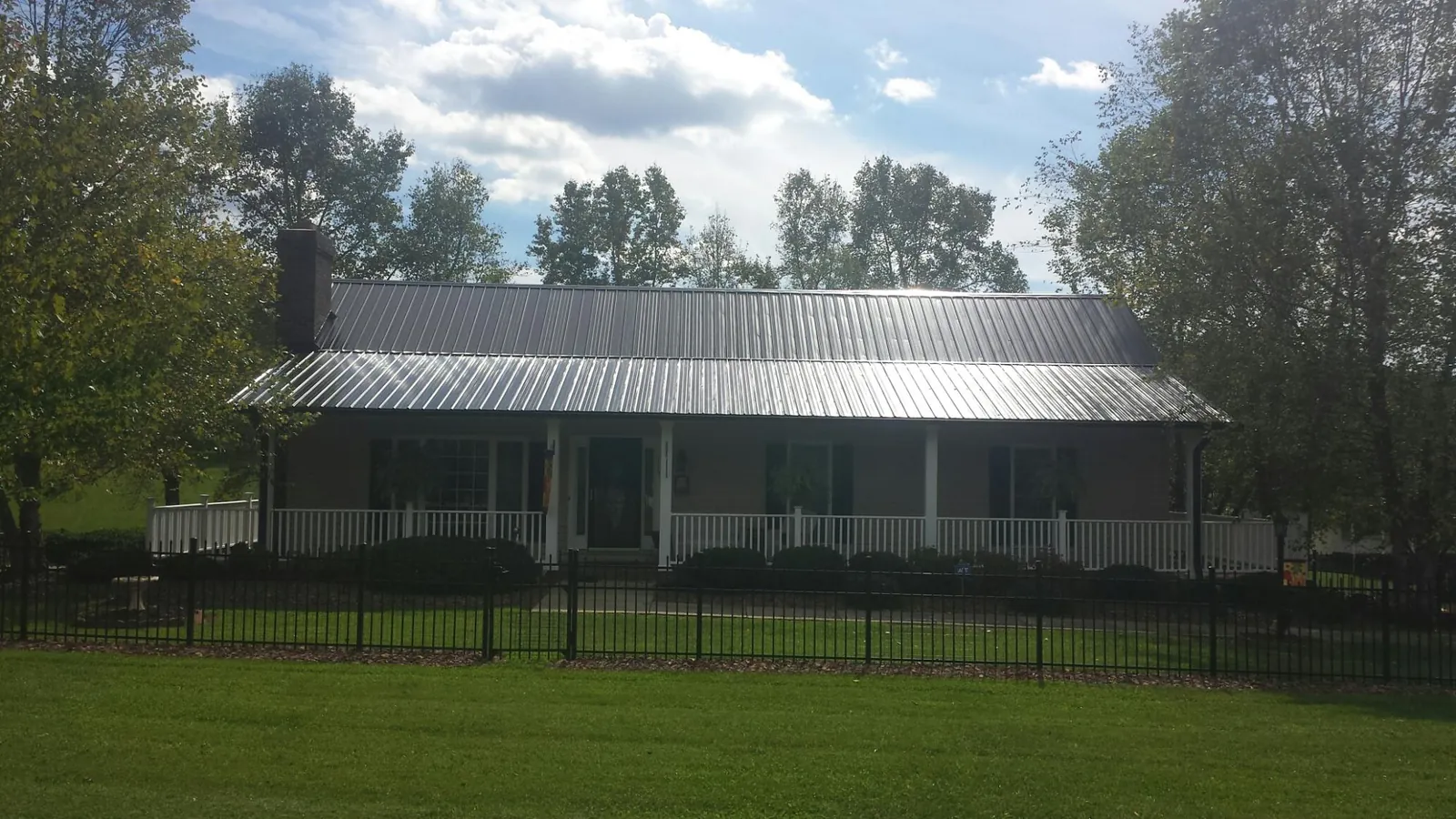 Gray metal roof on a brick ranch with a full width front porch — Gutter Guard Installation work by our crew in Country Club Hills