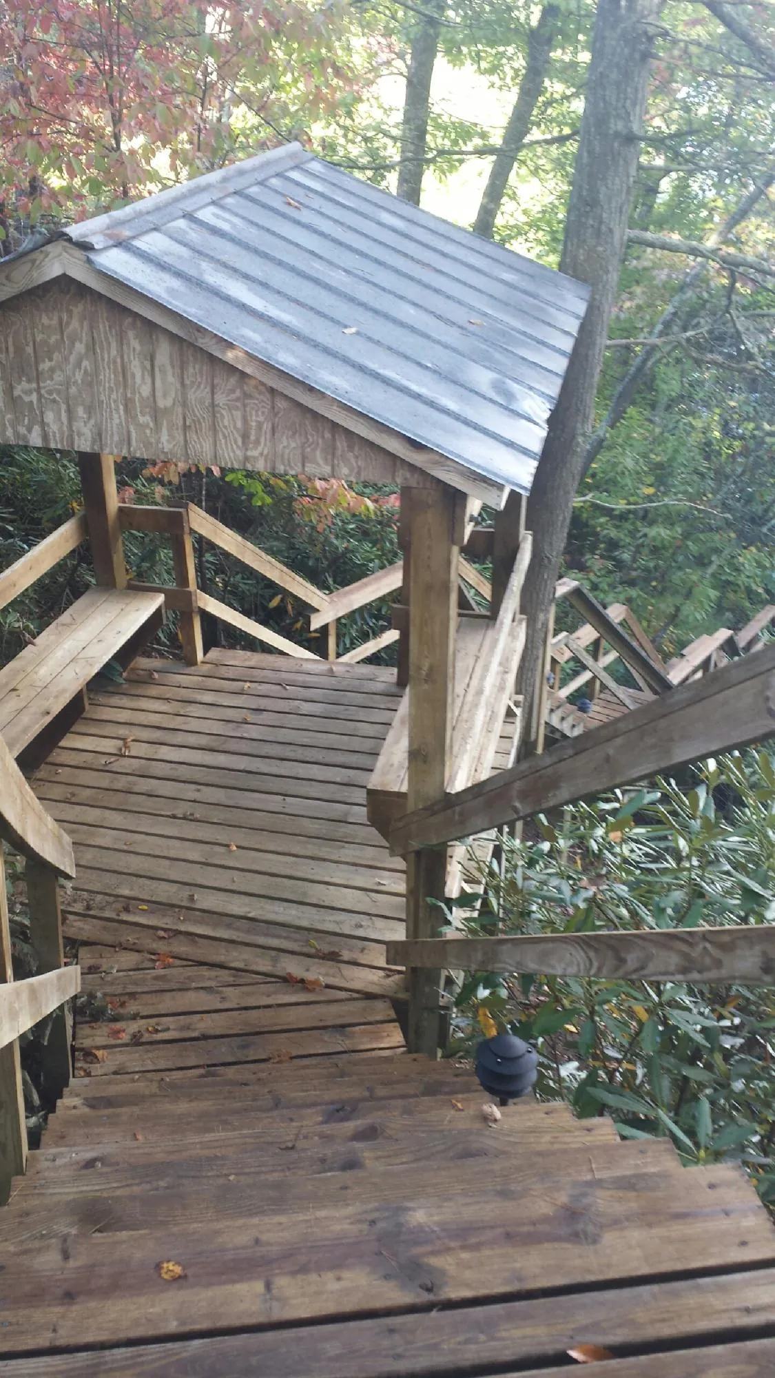 Metal roofed shelter over wooden steps on a wooded walkway — Skylight Repair & Installation work by our crew in Country Club Hills