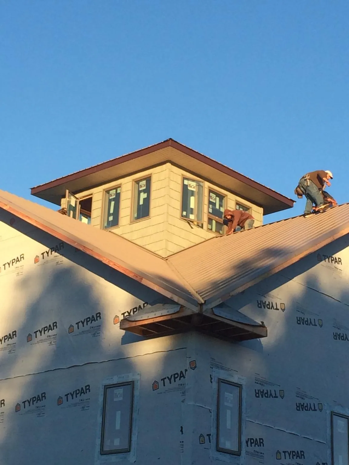 Roofers working around a rooftop cupola on a new metal roof at sunset — Roof Waterproofing in Country Club Hills by Roofing Brothers